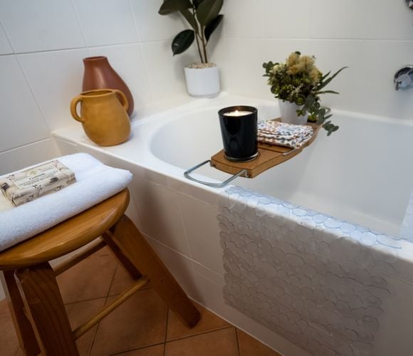 Bath with removable tray holding a candle, flowers and face towel