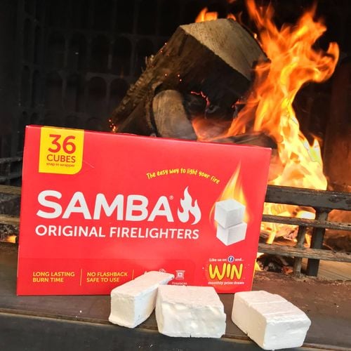Box of Samba 'Original Firelighters' next to three cubes of firelighter in front of a lit fireplace