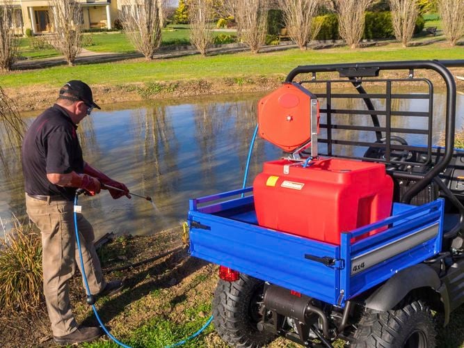 Small tank being used to spray near a creek 