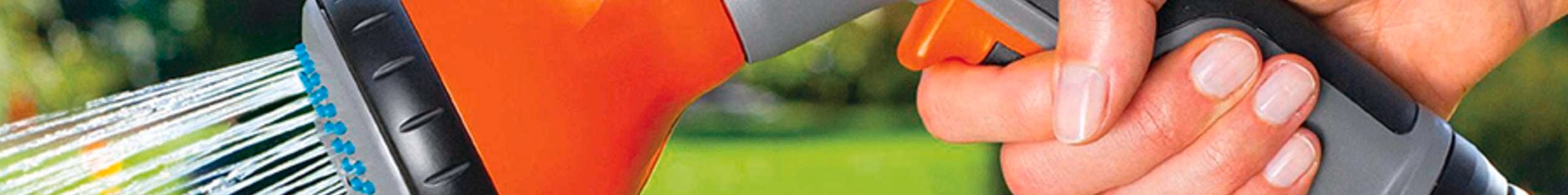 Image of a hand holding a Gardena hose with water spraying out of it.