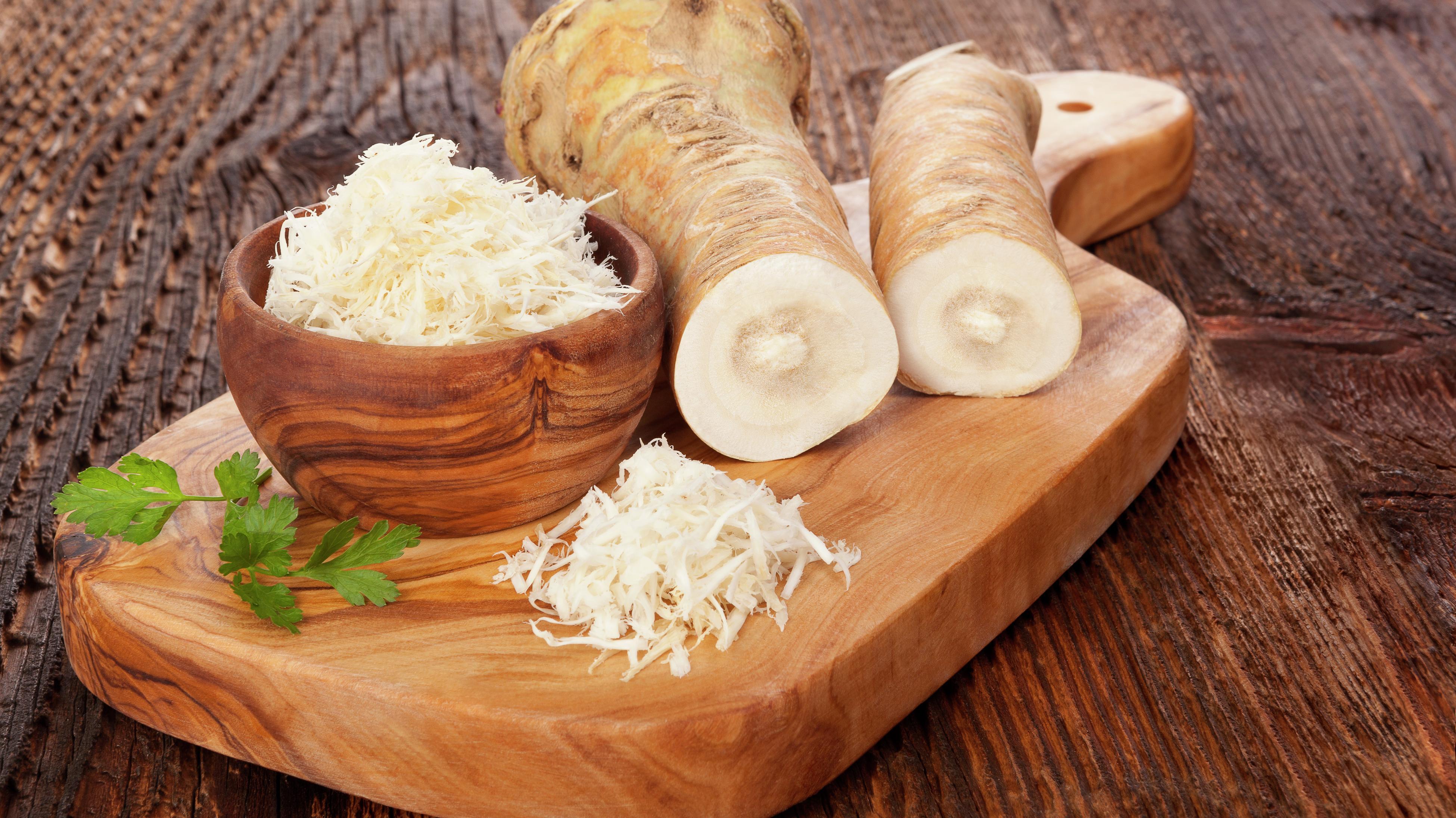 Horseradish on a chopping board and some grated in a bowl