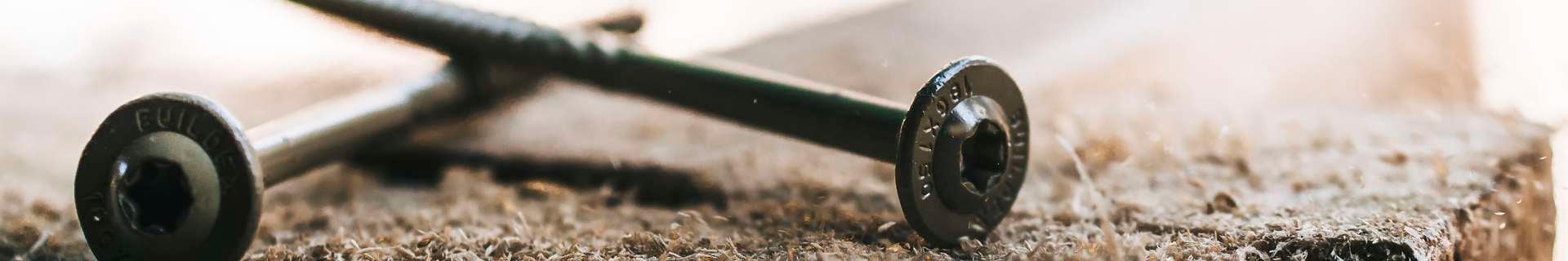 Close up of a screw on a bed of sawdust.