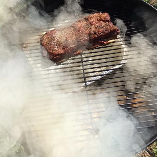 Person smoking meat on a kettle barbecue